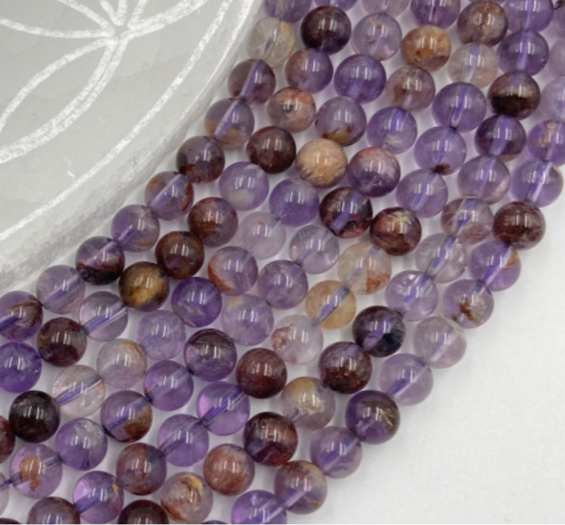 Améthyste 'super seven', perles rondes de 6 ou 8 mm, vendu : en fil de perle 38/39 cm, en bracelet de 17 à 21cm, en collier de 45 ou sautoir de 60cm. Qualité AA à AAA, superbes perles aux reflets violet, parfait !